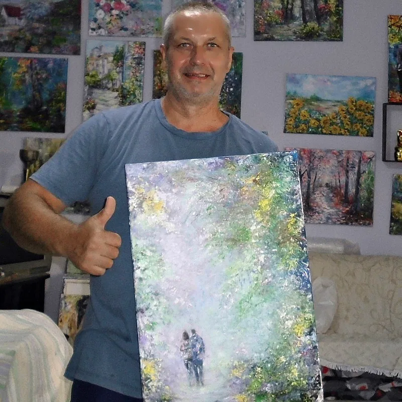 The artist holding a finished original oil painting in the studio before packing